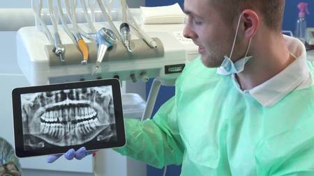 Dentist moves the x-ray image on his tablet