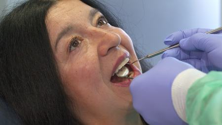 Dentist holds dental instruments in clients mouth