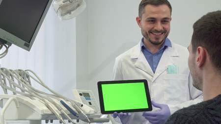 Dentist explaines something on the screen to his male patientの写真素材
