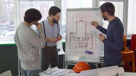 Architect explaining something on the plan of the building to his colleaguesの写真素材