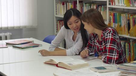 Female student sits down near her classmate at the library