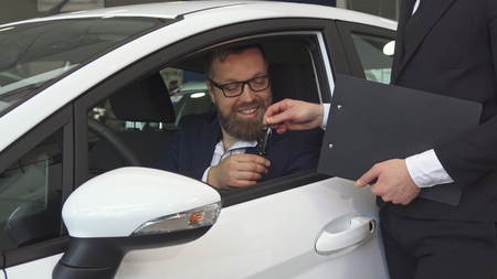 Male customer talks to the sales manager from inside the car