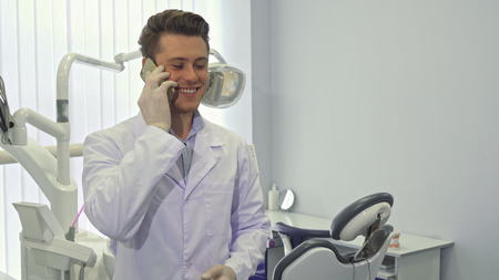 Dentist uses his cellphone at the officeの写真素材