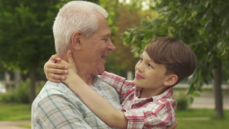 Little boy holds his hands behind his grandpas neck
