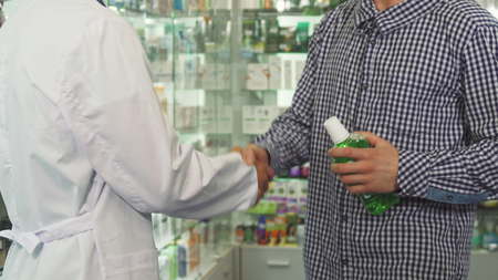 Doctor giving bottle of mouth-wash to patient and shaking handsの写真素材