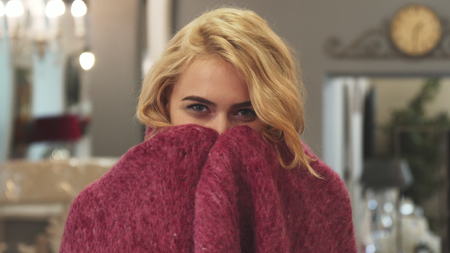 The happy girl wrapped herself in a blanket