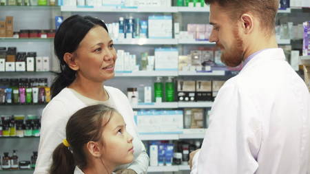Little daughter with her mom consult with the a pharmacistの写真素材