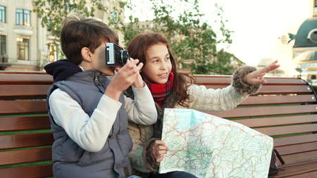 Young guys sit on a bench and take pictures of sightsの写真素材
