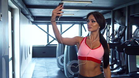 The sweet girl is making selfie on the background of the gymの写真素材