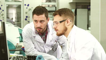 Attentive laboratory assistants discuss the results of tests that they see on the computer