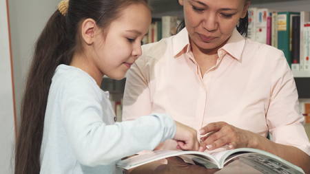 Mother and daughter choosing books at the library or bookstore