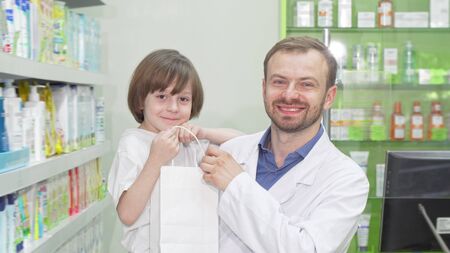 Cheerful pharmacist smiling to the camera with a cute little boyの写真素材