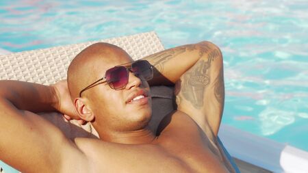 Cropped sliding shot of a happy African man relaxing at the poolsideの写真素材