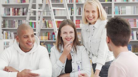 Cheerful young people enjoying talking at the college library after studyingの写真素材