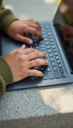 Focused hands typing on a sleek laptopの素材