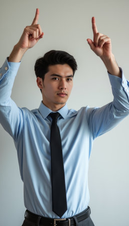 Confident young man gesturing upward with both handsの素材