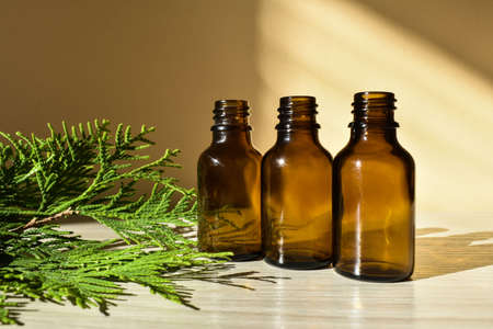 dropper bottle of brown glass and branch thujas against the yellow background. Beauty products packaging. Copy spaceの写真素材