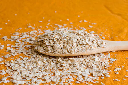 Dried oats or oatmeal in wooden spoon on the white table. Its are a nutrient-rich food associated with protein and fiber. . high quality photoの写真素材