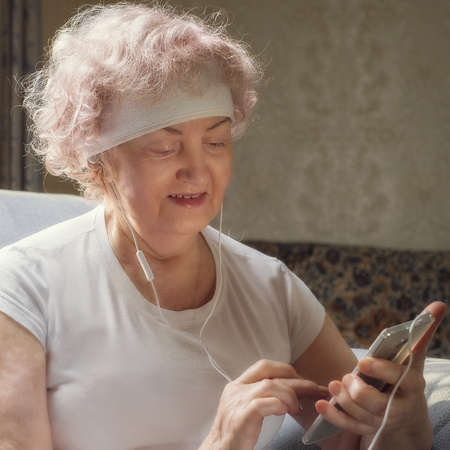 Elderly woman listening to music with a smile. Rest after fitness.の写真素材