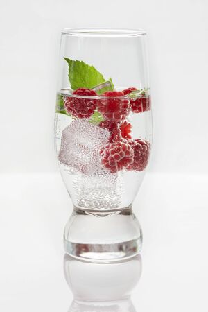 Fresh raspberries in a glass of mineral water and ice cubes on a white background.の写真素材