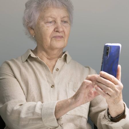 Happy elderly woman on the phone. Pensioner holding smartphone. An elderly lady takes selfie.