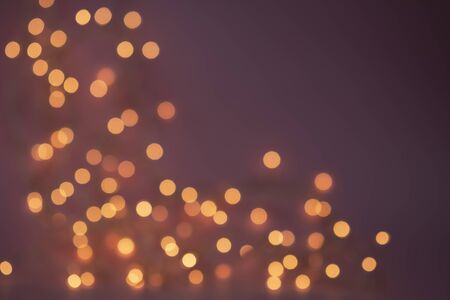 Abstract Christmas lights garland on dark purple background. Is defocused Glowing light bulb...
