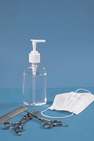 Hairdressing set, scissors comb and hand sanitizer with face mask on blue background.の写真素材