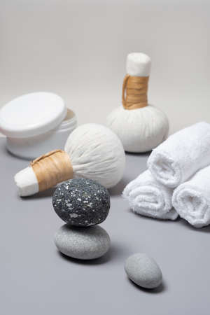Spa composition of herbal massage bags, a jar of salts, towels and stones.の写真素材