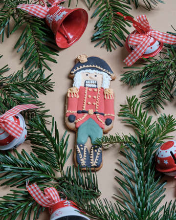 Ginger nutcracker cookies surrounded by pine needles with bells.