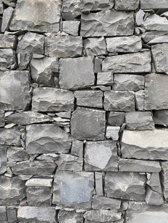 The wall is made of large and small gray stones, side view, textureの写真素材