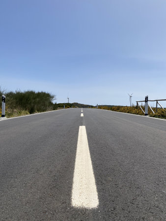 The road goes into the distance, paved, with wind turbines at the edgesの写真素材