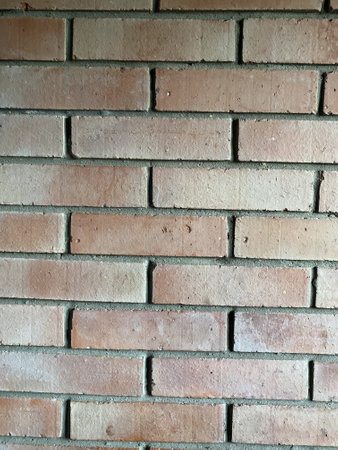 This is a side view of a brick wall, the color is red, the seams between the bricks are gray
