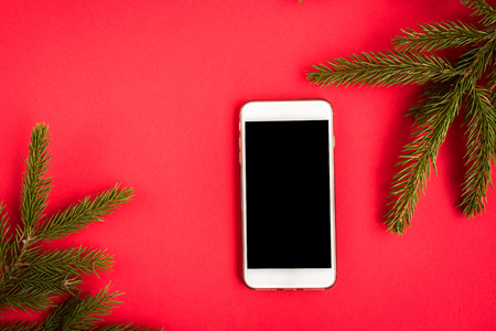 Mobile phone on red background with Christmas decorations and gifts. Xmas and Happy New Year composition.の写真素材