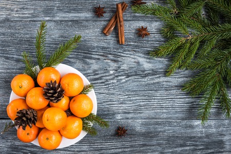 Mandarines on wooden background with Christmas fir branches, cinnamon sticks, anise stars and cones.の写真素材