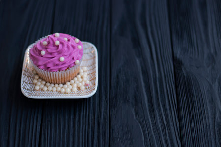 muffin with cream of lilac color decorated with edible pearls