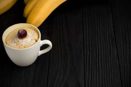 homemade cupcake in a mug stands on a black wooden backgroundの写真素材