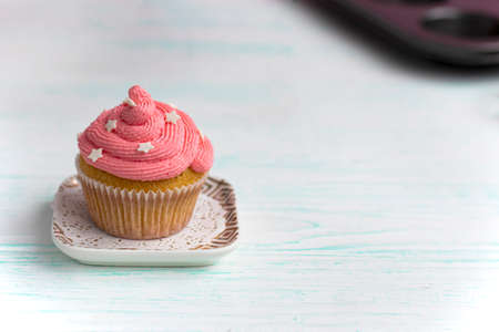 muffin with lilac color cream decorated with edible pearls