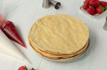 assembling strawberry cake on a light table. Ingredients for making a cake