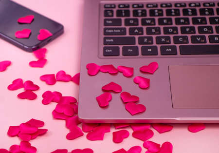 pink laptop lies on a pink background. telephone and scattered hearts.の写真素材