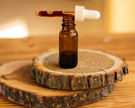 a drop of serum with a pipette drips over a brown glass jarの写真素材
