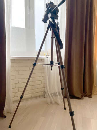 Tripod in the bedroom of warm colors with tulle developing from the wind.