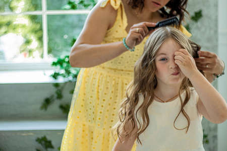 mother combs her daughter before the performance. Tangled baby hair.の写真素材