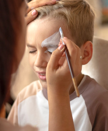 Master making aqua makeup on boys face. face painting kids.
