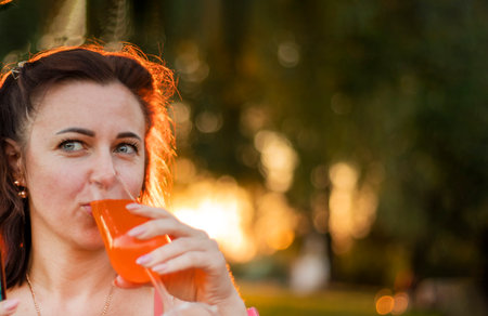 happy woman holding glass of fresh orange juice outdoorsの写真素材