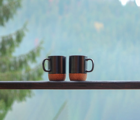 Two steaming cups of coffee on a wooden balcony with mountain viewの写真素材