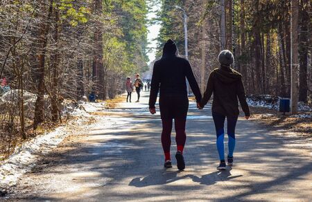 Young guy and a young girl are walking in the park holding hands. Loving couple on a walk.の写真素材