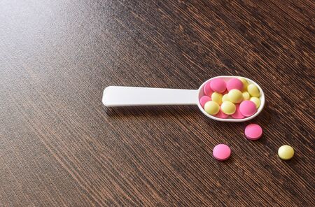 Colored pills on the table. Medical drugs on a dark background. Place for text.の写真素材