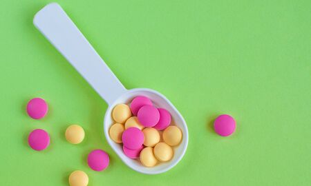 Colored pills on the table on  green
