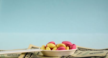Colored pills in a medical spoon and american dollars. Economic crisis. The cost of treatment. Selective focus. Copy space.の写真素材