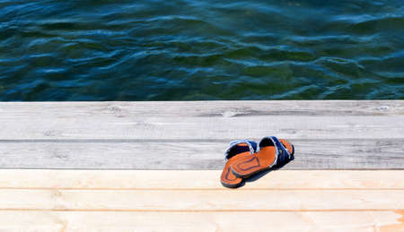 Womens beach shoes on wooden background, vacation concept. Blurred marine background.の写真素材